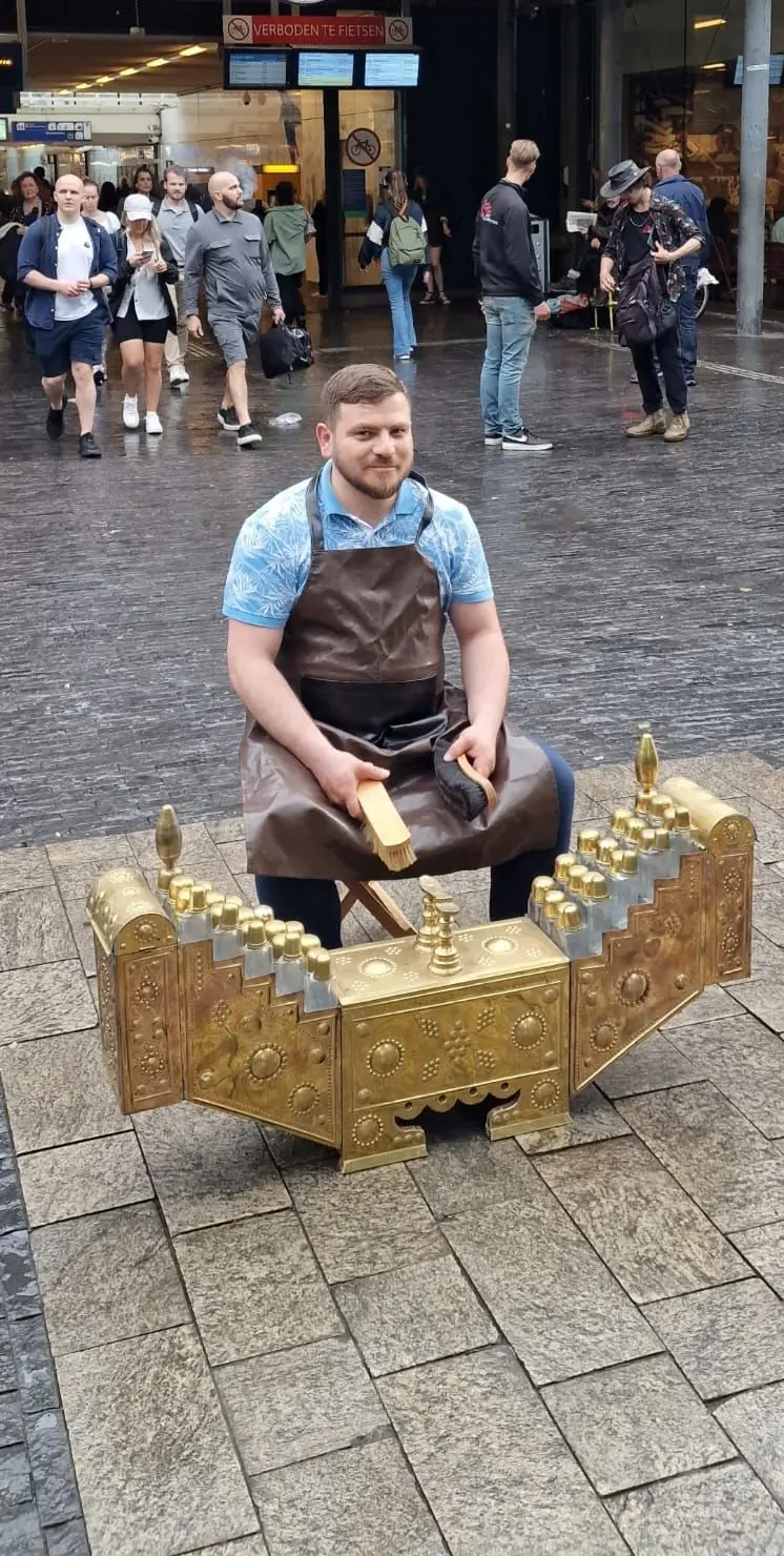 Ali met zijn schoenpoetsstoel en materialen op straat in Amsterdam